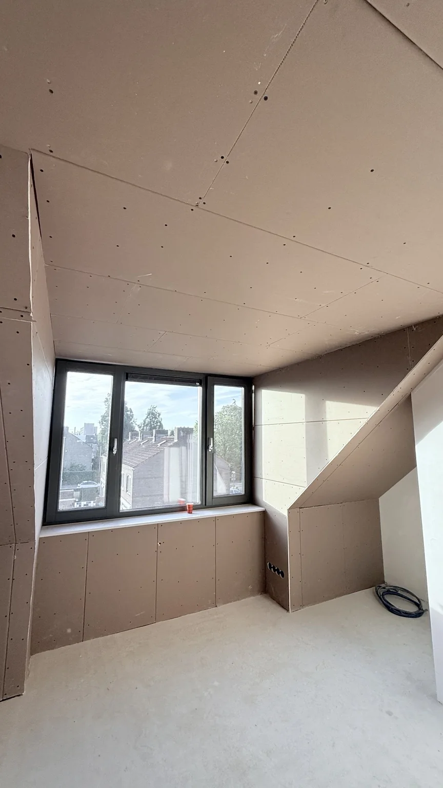 Zolderkamer met gipsplaten, schuine wand en ramen