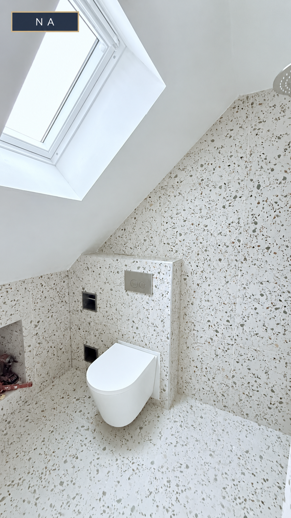 Na de badkamerrenovatie: wandtoilet onder het dakraam met terrazzo tegelwerk