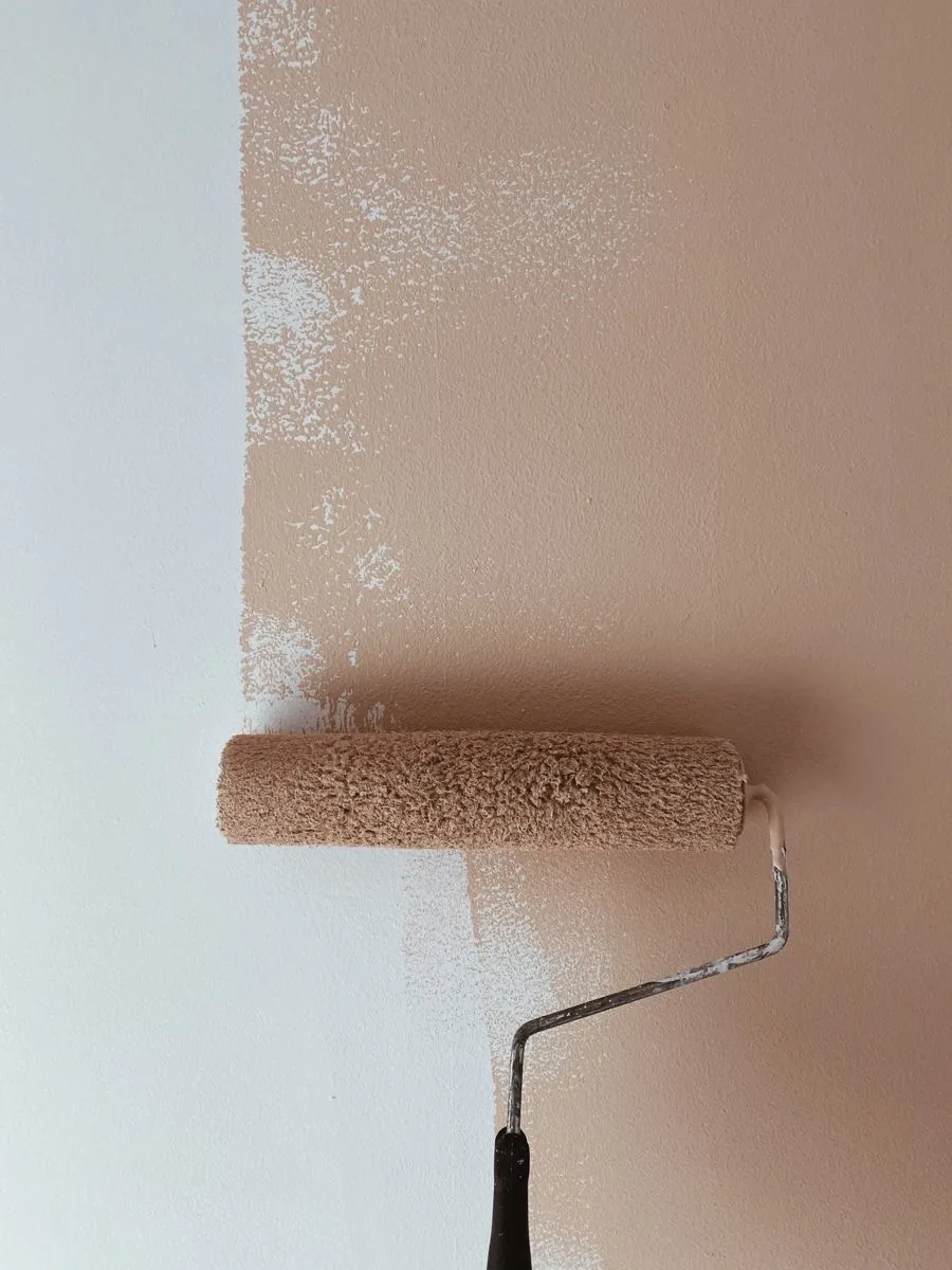 Verfroller brengt beige verf aan op een muur