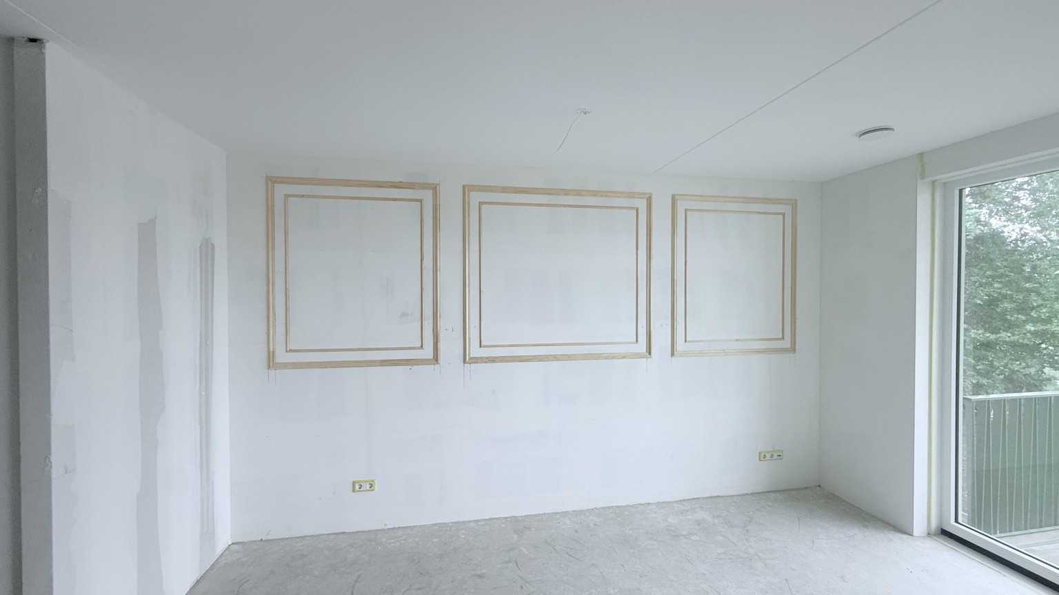 Wand met houten sierlijsten tijdens de afwerking